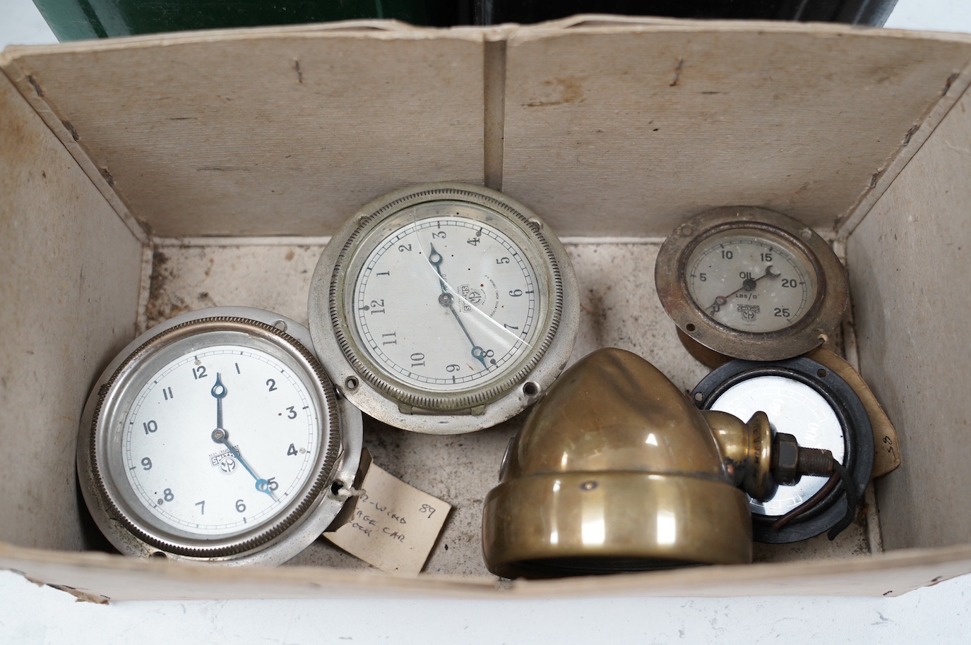 Three early Smiths car timepieces, two oil pressure gauges, a small brass headlamp and two petrol cans with brass caps, one embossed ‘Esso’ with corresponding casting on cap, the other unmarked. Condition - poor to fair